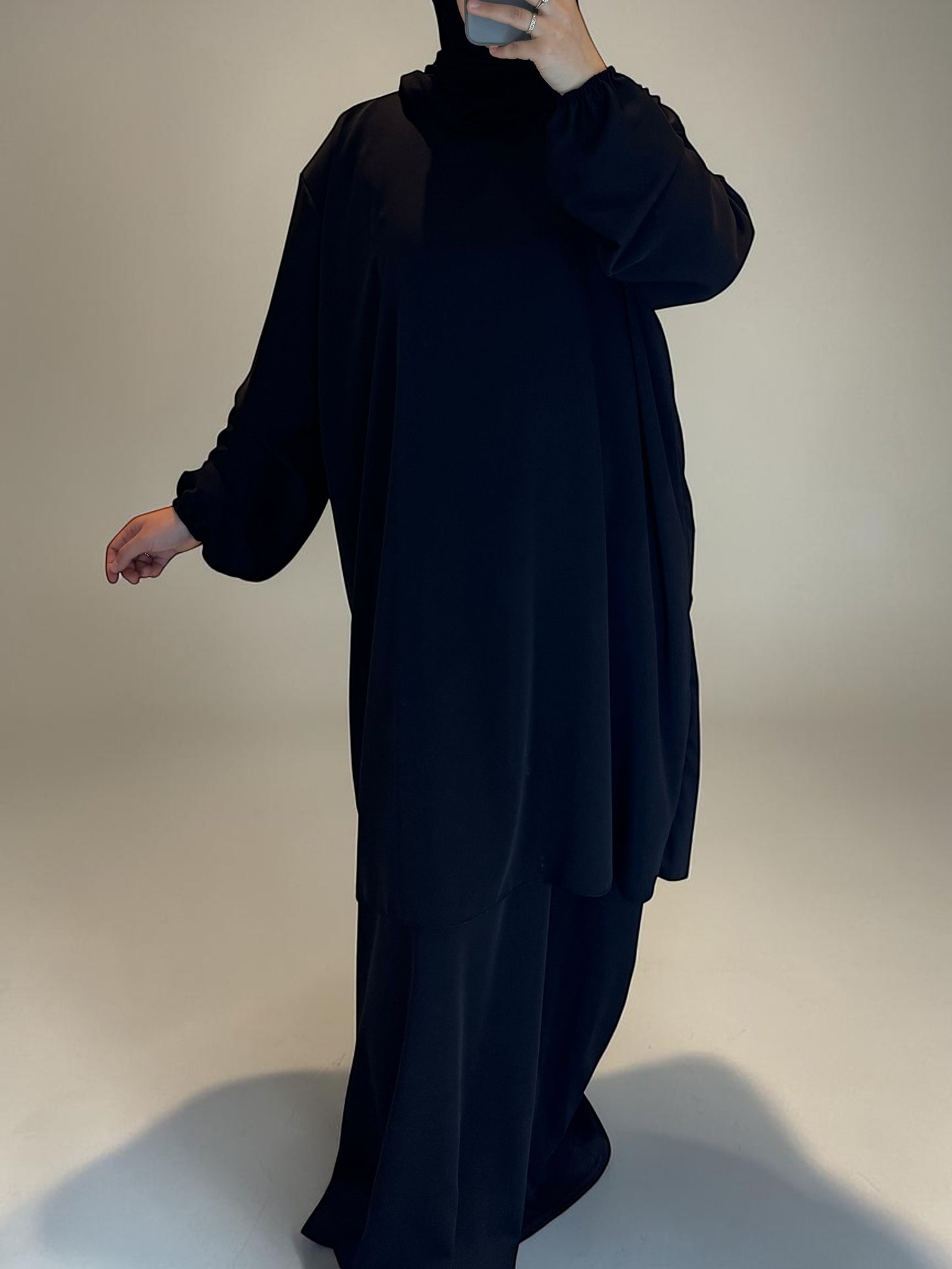 Nesthetics black 2-in-1 Abaya made of Medina silk, featuring a long tunic over a flowing skirt. Standard size, 140cm length.