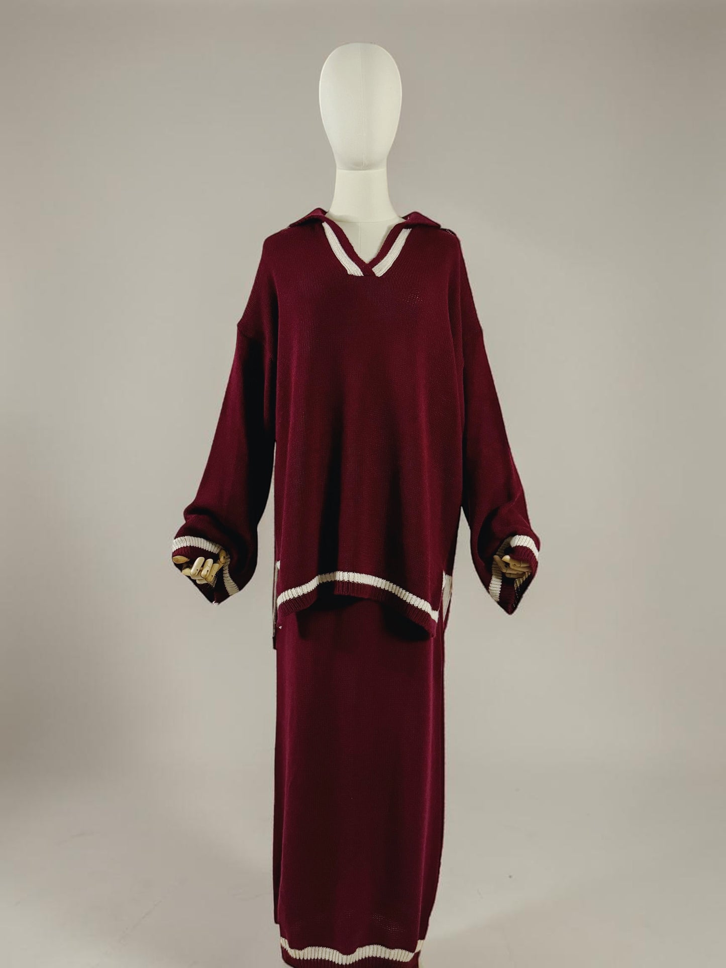 Nesthetics burgundy knit sweater with V-neck and white trim, paired with a matching midi skirt. White striped cuffs and hem.