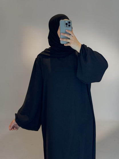 Nesthetics Abaya Malika aus Jazz Stoff mit Ballonärmeln in Schwarz. Bequem und vielseitig.