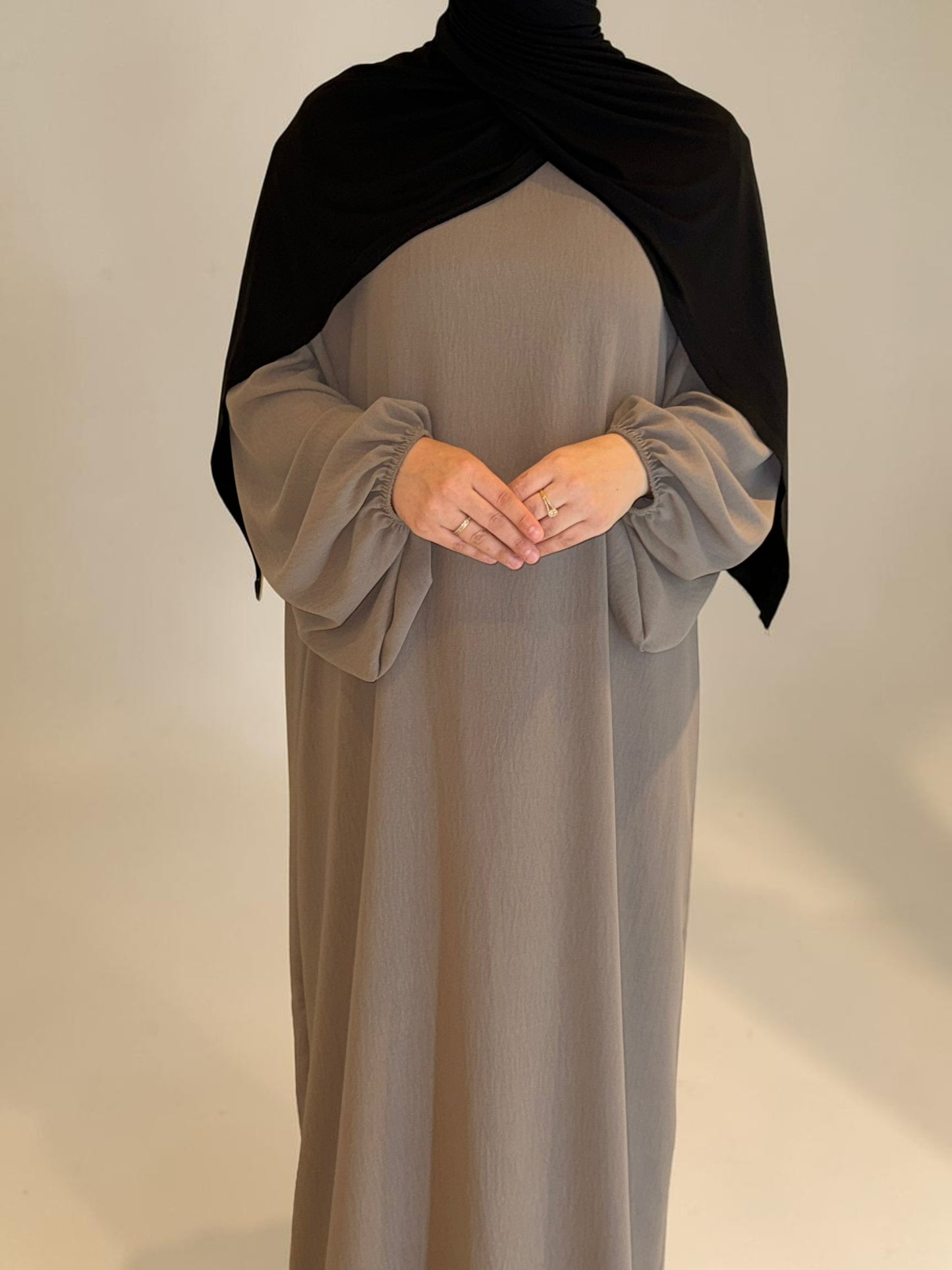 Nesthetics Abaya Malika aus Jazz Stoff mit Ballonärmeln in Taupe, mit schwarzem Hijab.