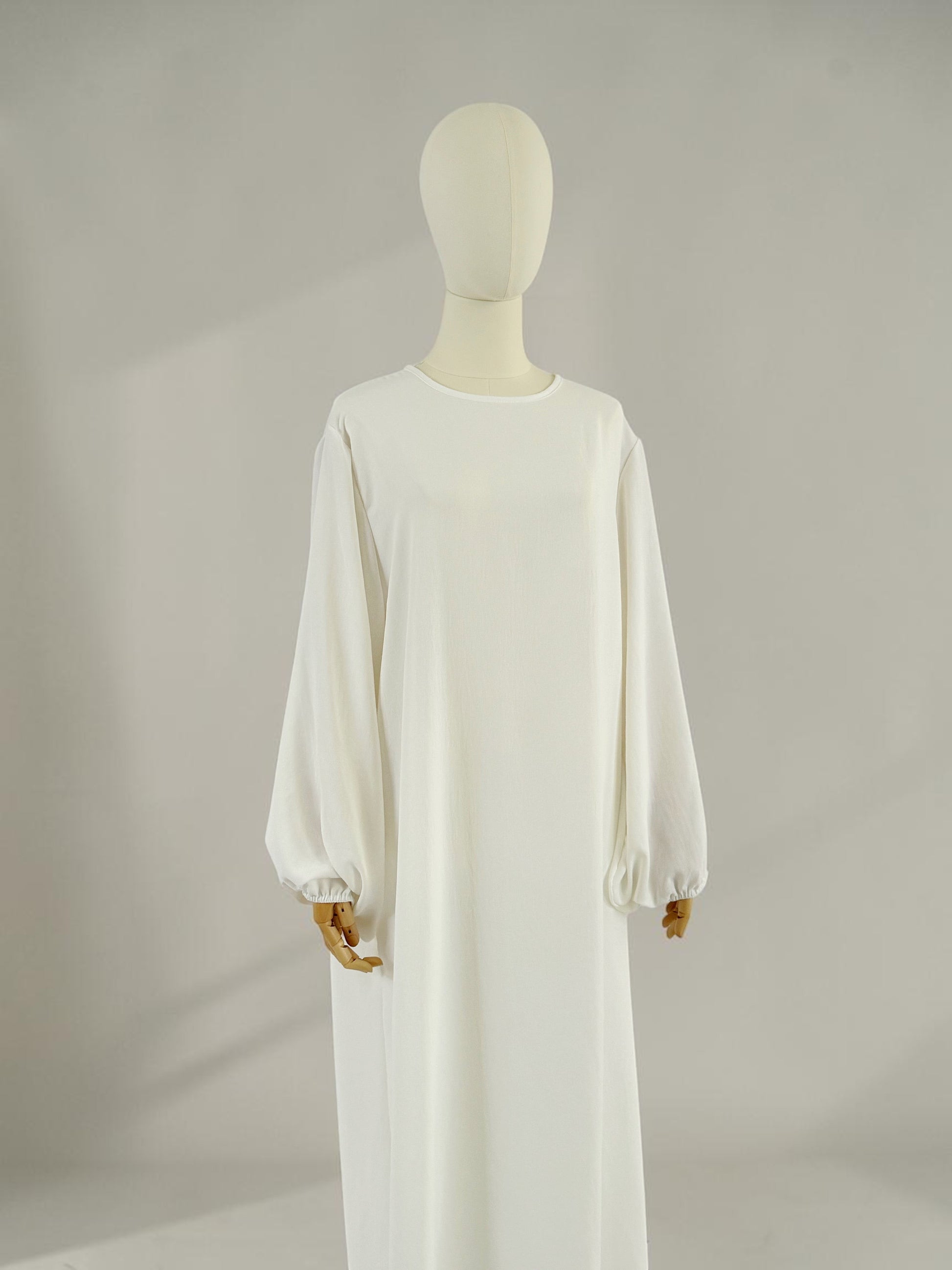 Nesthetics weiße Abaya Malika aus Jazz Stoff mit Ballonärmeln, Rundhalsausschnitt und langem Schnitt.