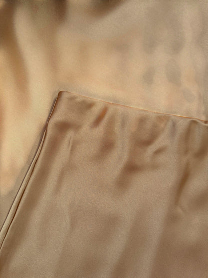 Nesthetics champagne satin midi skirt with a flowing drape and luxurious sheen, perfect for elegant occasions.