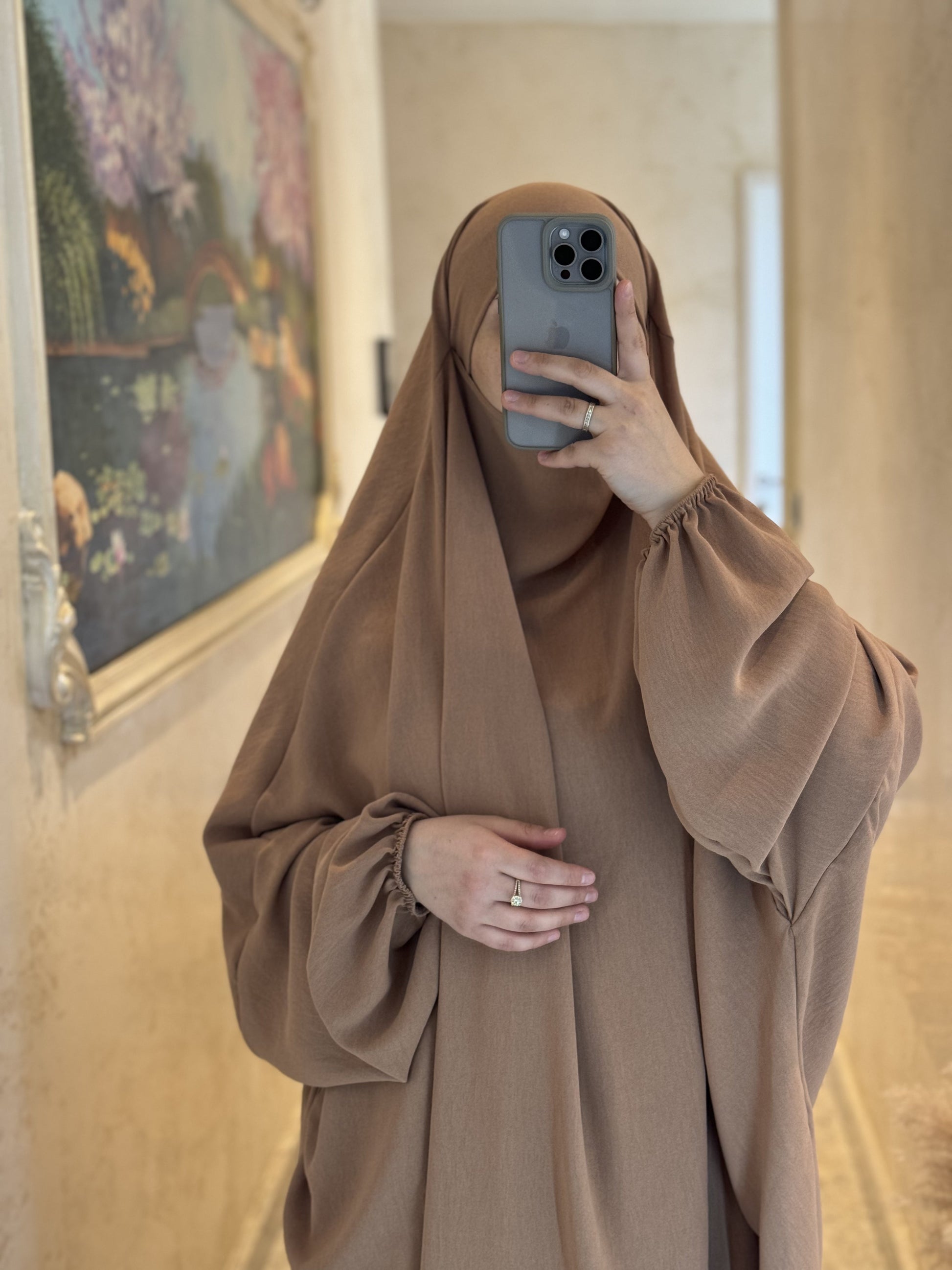Nesthetics Jazz Jilbab in Camel mit elastischen Ärmelbündchen, getragen von einer Frau vor einem Wandgemälde.