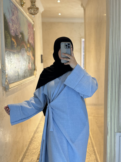 Nesthetics light blue linen-look wrap abaya with wide sleeves and a round neckline.